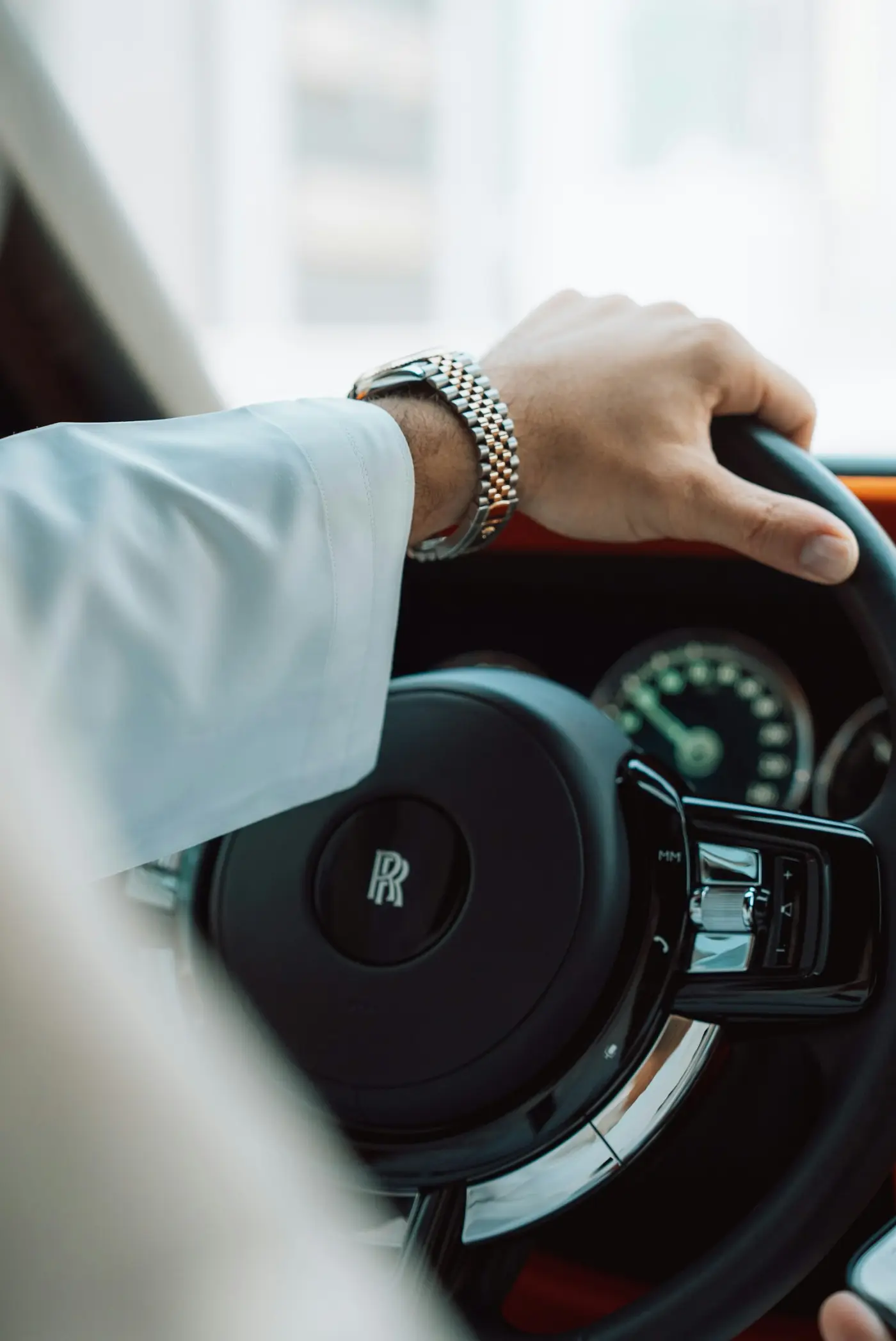 Professional chauffeur driving — hands on the leather steering wheel of a luxury European executive vehicle
